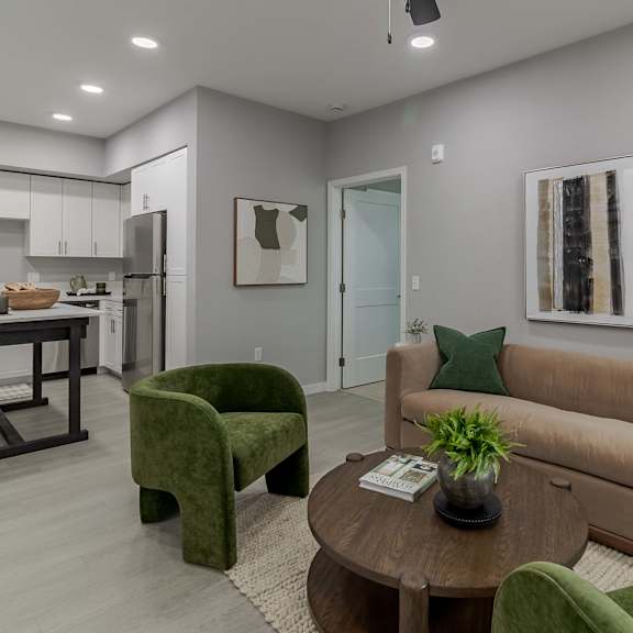 a modern living room with a green armchair and a brown sofa.
