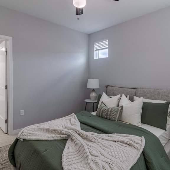 a bedroom with a bed covered in a green blanket and pillows.