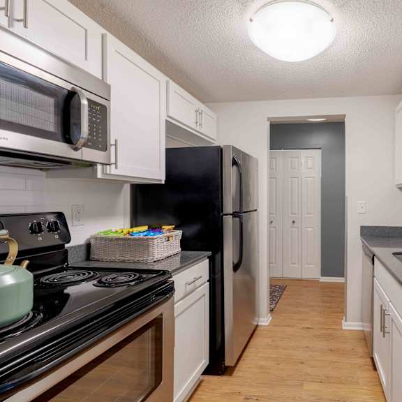 a kitchen with black and white appliances and wooden floors.