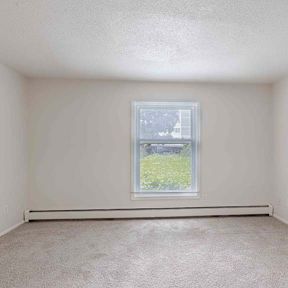 a room with a window and carpeted floor.