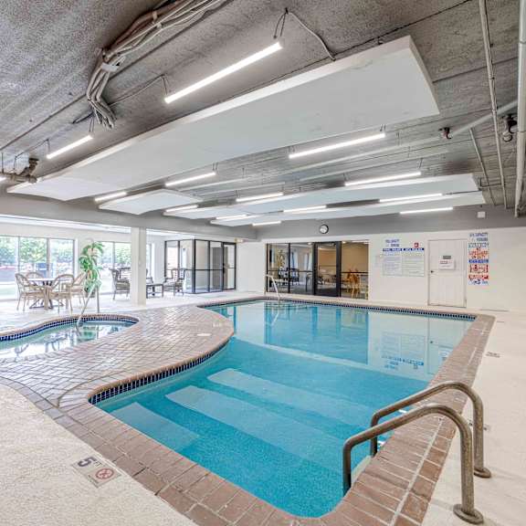 a large indoor swimming pool with a mosaic tile edge and a metal ladder.