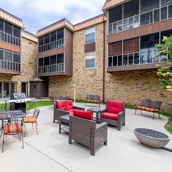 a patio area with a table and chairs in front of a brick building.