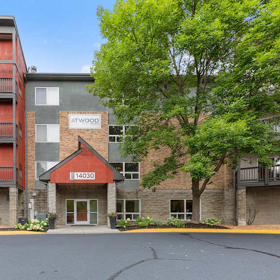 an apartment building with brick and stone exterior and trees