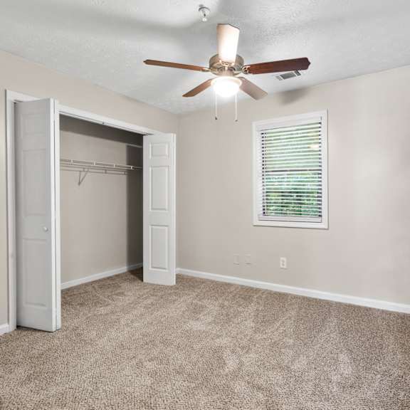 a room with a ceiling fan and a window with blinds.