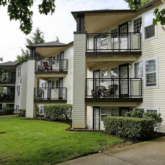 an apartment building with balconies and a grass yard at sundial apartments, wilsonville