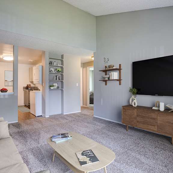 a living room with a grey carpet and a wooden coffee table.