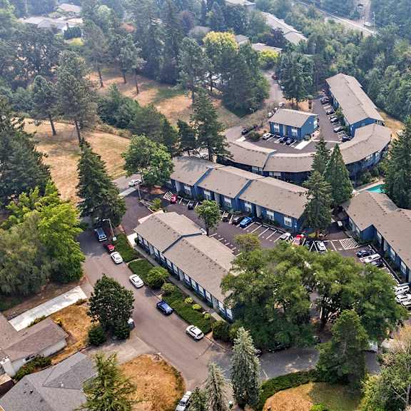 a large building surrounded by trees and a parking lot.