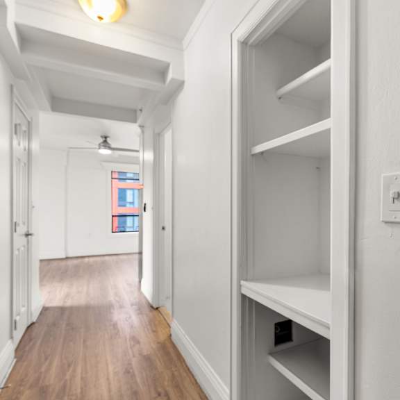 a long hallway with a door on the left and an empty shelf on the right at the exeter apartments, seattle, washington