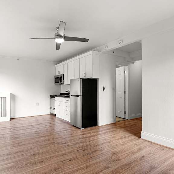 a spacious kitchen with white cabinets and a black refrigerator at the exeter apartments, seattle, wa, 98101