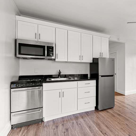 a kitchen with white cabinets and a black fridge at the exeter apartments, washington