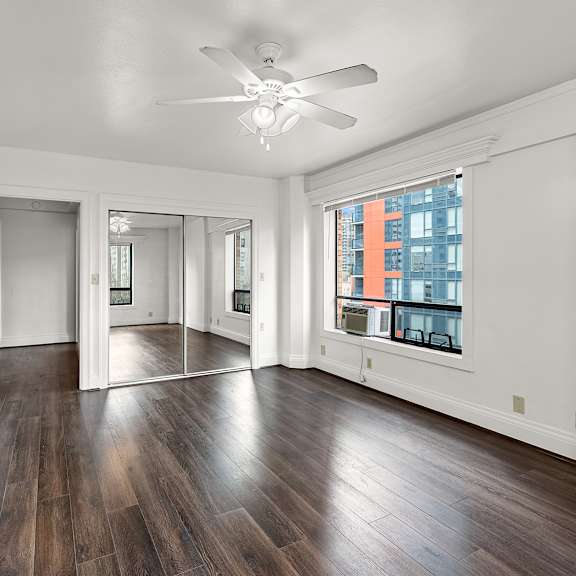 a spacious room with wooden floors and a ceiling fan at the exeter apartments, washington, 98101