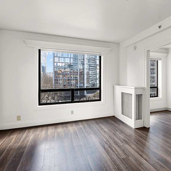 a large empty room with a window and wood flooring at the exeter apartments, seattle, washington