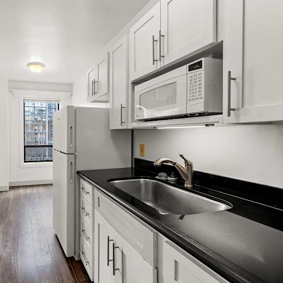 a kitchen with white cabinets and black countertops at the exeter apartments, seattle, wa, 98101