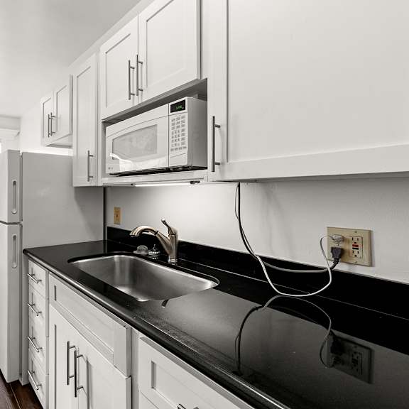 a kitchen with black countertops and white cabinets at the exeter apartments, seattle, wa, 98101
