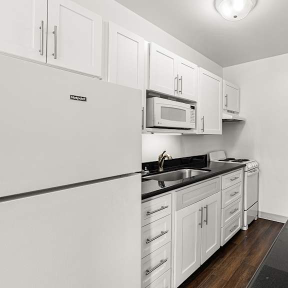 a kitchen with white cabinets and black countertops at the exeter apartments, seattle, 98101