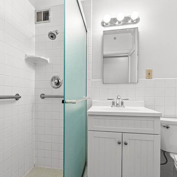 a white tiled bathroom with a blue shower door at the exeter apartments, seattle, washington