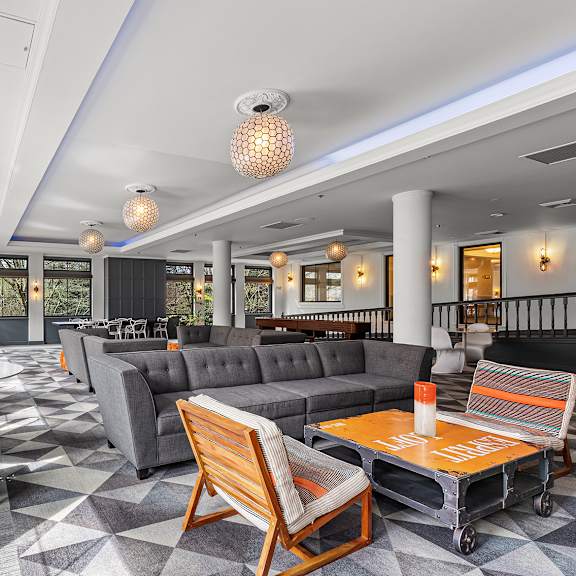 a large room with a grey sofa, a wooden chair and a table at the exeter apartments, apartments, seattle, wa