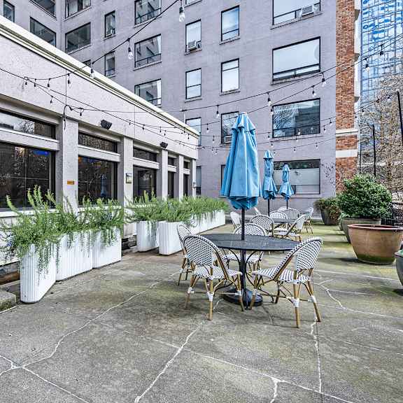 a patio with a table and chairs is surrounded by potted plants at the exeter apartments, seattle, washington