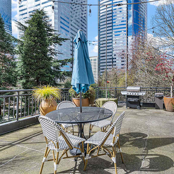 a patio with a table and chairs overlooking a cityscape. at the exeter apartments, seattle, washington