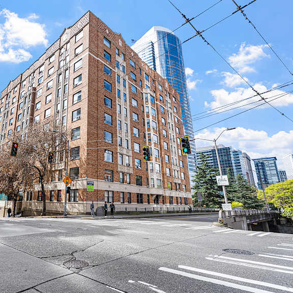 a large brick building is situated on a street corner with a traffic light and a street sign at the exeter apartments, seattle