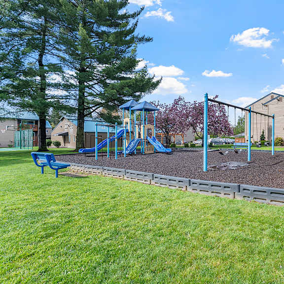 a playground with a slide and a blue bench.