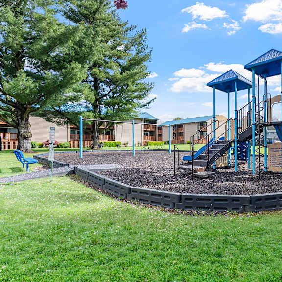 a playground with a blue swing set and a round sandbox.