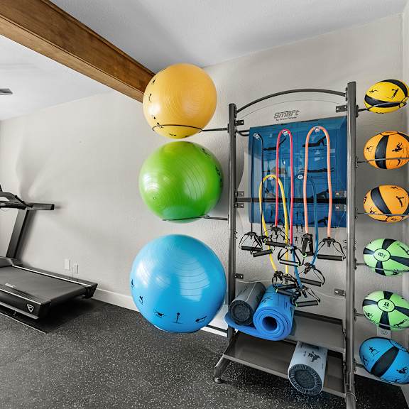 a home gym with a treadmill, exercise balls, and resistance bands.