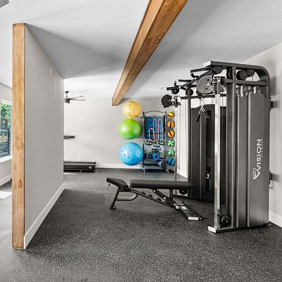 a home gym with a treadmill, exercise balls, and weights.