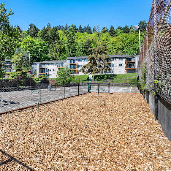 a playground with a brown surface and a fence surrounding it.