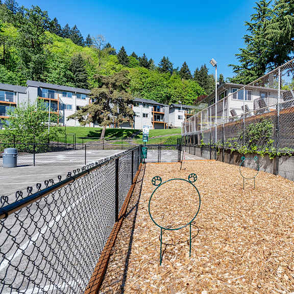 a playground with a green monkey swing set sits in the middle of a wood chip area.