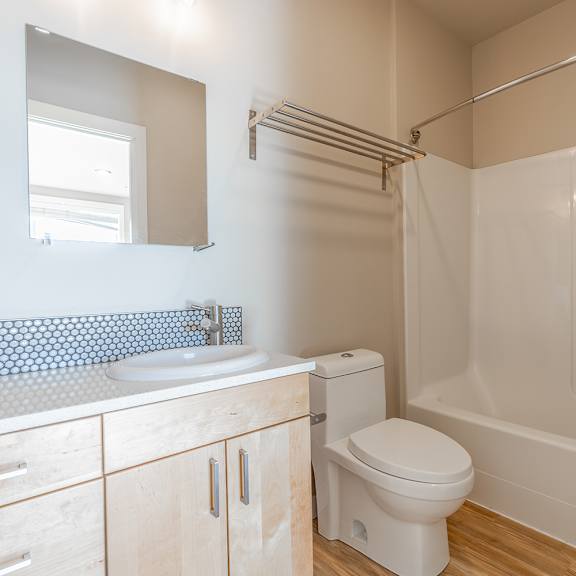 modern bathroom with light wood vanity and tub at brooklyn yard apartments, portland, or