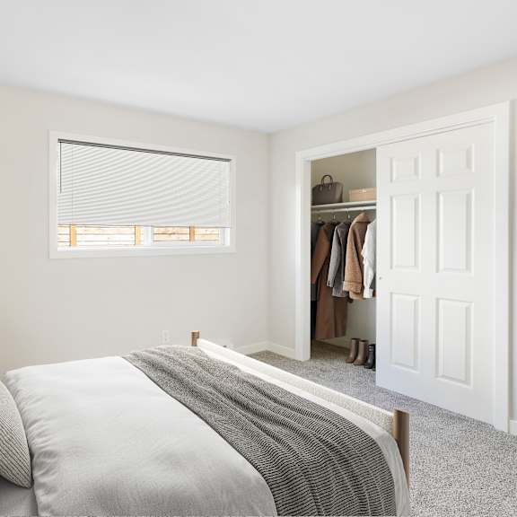 a bedroom with a bed, pillows, a lamp, and a closet.
