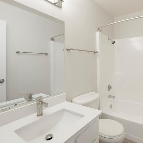 a white bathroom with a sink, toilet, and bathtub.