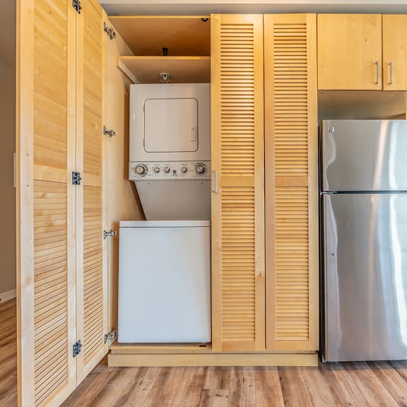 stacked washer dryer behind louvered cabinet doors at brooklyn yard apartments, oregon, 97202