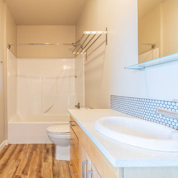 bathroom with glass shower and penny tile backsplash at brooklyn yard apartments, portland, or