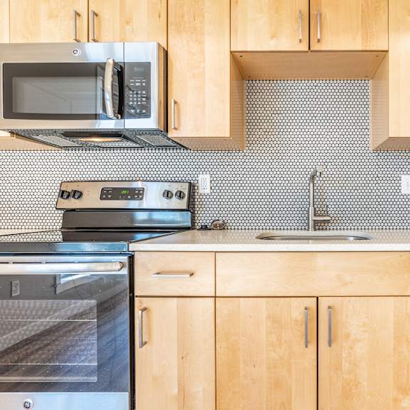 contemporary kitchen with penny round tile and light wood cabinetry at brooklyn yard apartments, portland, or 97202