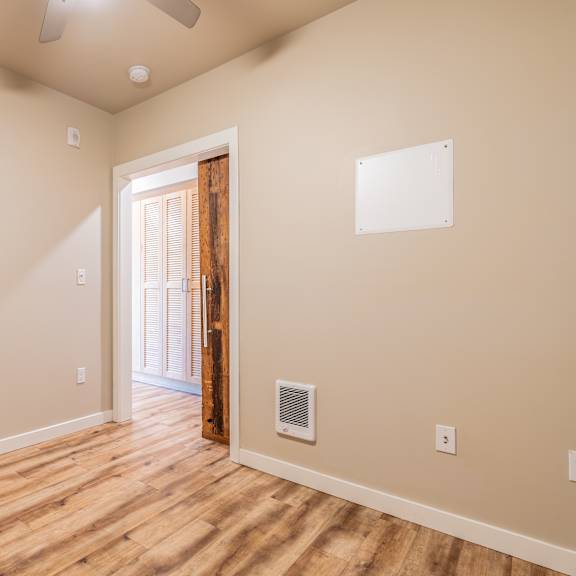empty room with rustic wood door accent and ceiling fan at brooklyn yard apartments, portland