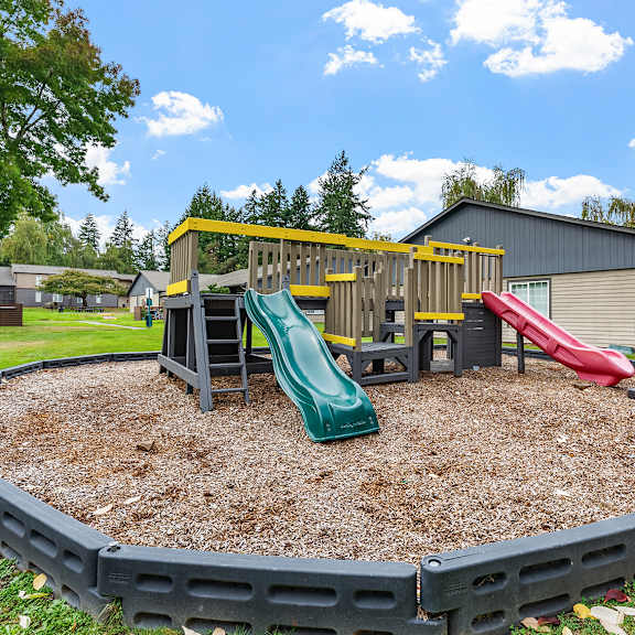 a playground with a green slide and a red slide.