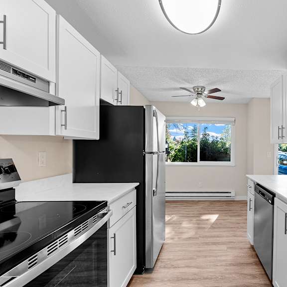 a kitchen with white cabinets, refrigerator and a window