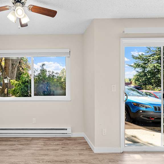 a room with a ceiling fan, wooden floors and windows