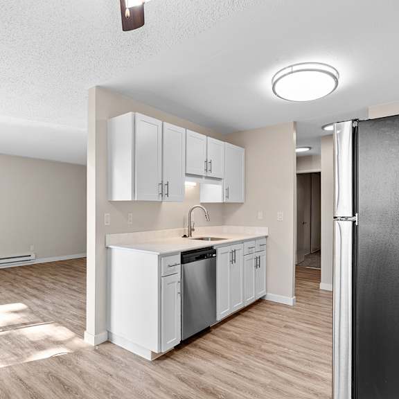 a kitchen with white cabinets and a black refrigerator and a view of the living room