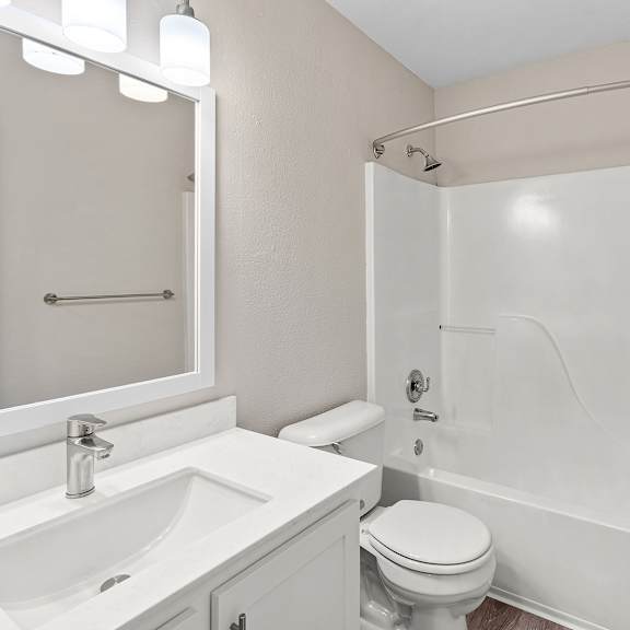 a white bathroom with a toilet, sink, and shower.
