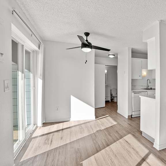 a white room with a ceiling fan and wooden flooring.