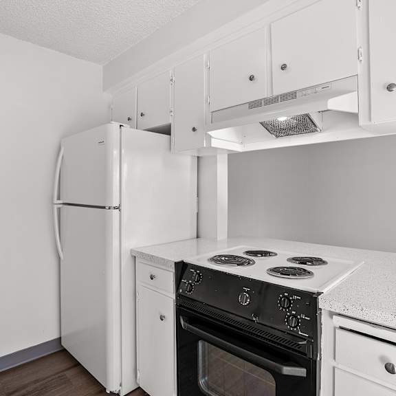 a white kitchen with a refrigerator, oven, and stove.