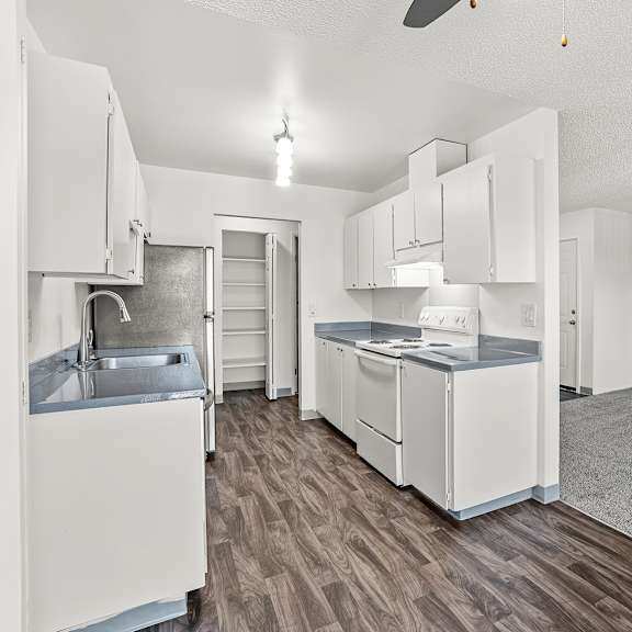 a kitchen with white appliances and wooden floors.