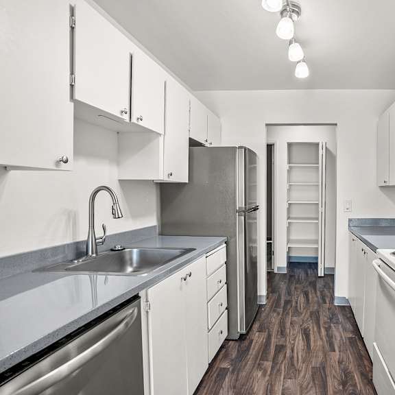 a kitchen with white appliances and cabinets and wooden floors.