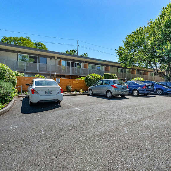 a parking lot with cars and a building in the background.