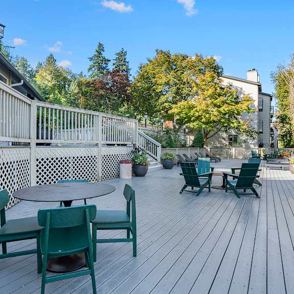 a wooden deck with green chairs and a table.