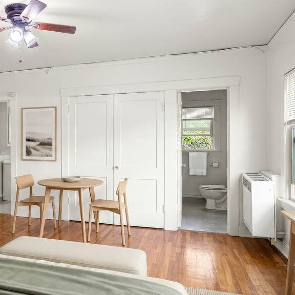 a bedroom with a bed, a table and chairs, and a ceiling fan.