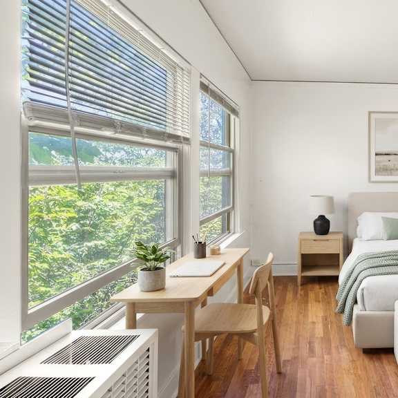 a bedroom with a bed, a table, and a ceiling fan.